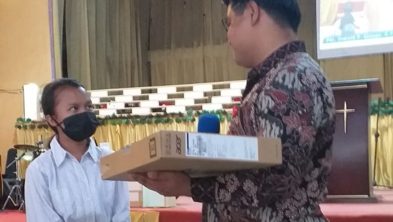 Pdt Donald Sinaga, Gembala Jemaat GEPKIN menyerahkan bantuan 1 unit laptop kepada Indah Nainggolan, siswa berprestasi dari SMAN 1 Doloksanggul.