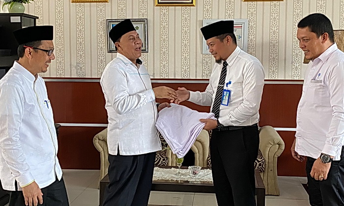 Pelaksana harian (Plh) Direktur Utama Perumda Tirtanadi Ewin Putra menyerahkan secara simbolis handuk untuk jamaah haji Embarkasi Medan di Asrama Haji Medan, Senin (13/5/2024).